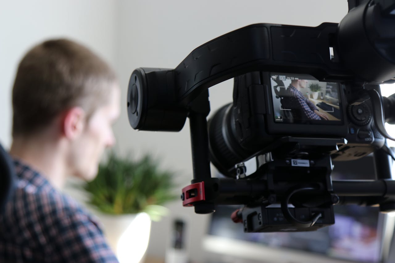 service-02 Close-up of camera filming a man in an indoor setting, highlighting professional video production