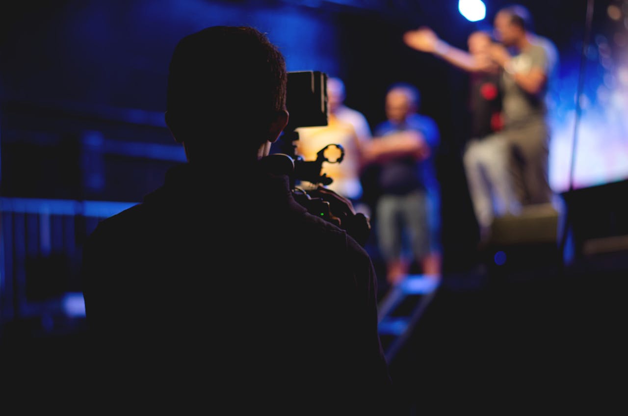 service-01 A cameraman films a live concert performance, capturing the dynamic stage action.