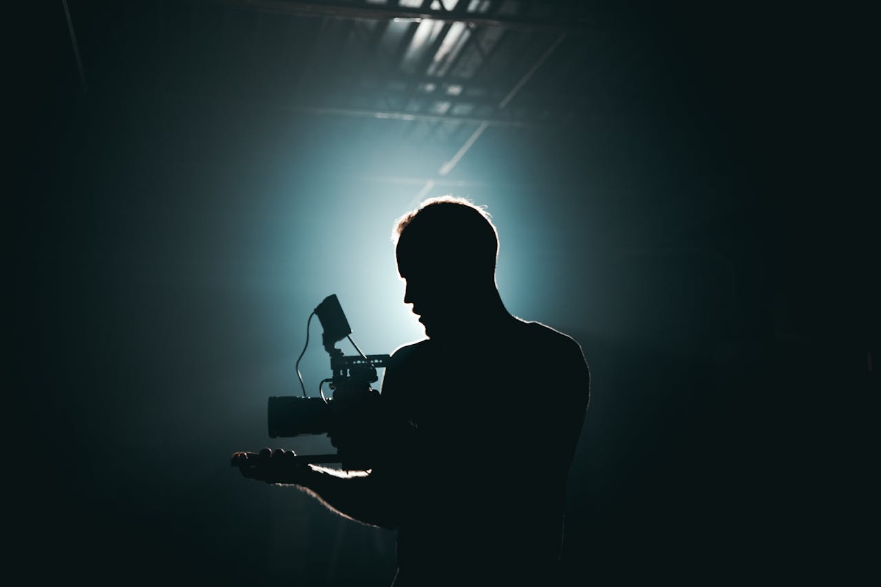 about-me-img Silhouette of a cinematographer with camera gear in a dramatic, low light setting.