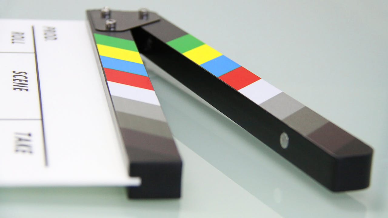 why-choose-me Colorful clapper board on a white surface, used in filmmaking. Ideal for entertainment and movie themes.